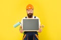 man housepainter in helmet and work clothes hold paint roller brush and blackboard with copy space