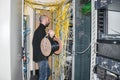 Man with a hub of utp cable works in the server room of the data center. The technician is near the racks with the servers. The