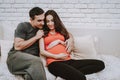 Husband and Pregnant Wife Relaxing on Couch Royalty Free Stock Photo