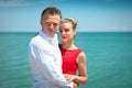 Man is hugging a woman delicatly posing with her by the sea.