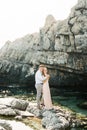 Man hugs woman standing on the rocks in the water near the cliff Royalty Free Stock Photo