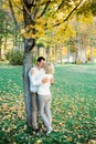 Man hugs woman standing under a plane tree with yellow leaves Royalty Free Stock Photo