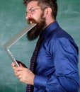 Man hungry for knowledge. Thirst of knowledge. Teacher bearded man bites modern laptop chalkboard background. Hipster Royalty Free Stock Photo