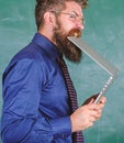 Man hungry for knowledge. Thirst of knowledge. Teacher bearded man bites modern laptop chalkboard background. Hipster Royalty Free Stock Photo