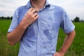 Man with hyperhidrosis sweating very badly under armpit in blue shirt, on grey