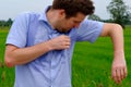 Man with hyperhidrosis sweating very badly under armpit in blue shirt, isolated on grey