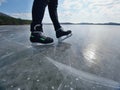 Man ice skating on frozen lake. Thin ice with deeep cracks below man Royalty Free Stock Photo
