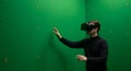 Man immersed in virtual reality with headset against green screen backdrop Royalty Free Stock Photo