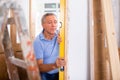 Man independently measures deviations from given vertical wall of door jamb using building level