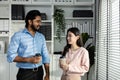 Man indian and asian woman holding coffee cup talking for work relax time standing in modern office. Asian business people meeting Royalty Free Stock Photo