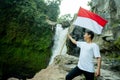 Man with indonesian flag of indonesia in waterfall with beautiful view
