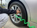 A man inflates his car tires with an air pump tube