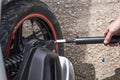 A man inflates a tire on a motorcycle with an air compressor. Maintenance of motorcycle equipment