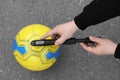 Man inflating ball with manual pump on asphalt, top view