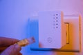 Man insert ethernet cable into WiFi extender device which is in