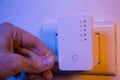 Man insert ethernet cable into WiFi extender device which is in