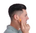 Man inserting foam ear plug on white background Royalty Free Stock Photo