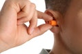 Man inserting foam ear plug on white background, closeup Royalty Free Stock Photo