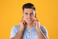 Man inserting foam ear plugs on yellow background Royalty Free Stock Photo