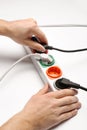 Man inserting power plug into extension cord on white background, closeup. Electrician`s professional Royalty Free Stock Photo