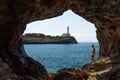 Man inside cave, view Lighthouse Portocolom in Mallorca.