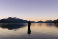 Man inside Lake Wakatipu looking at the amazing sunset behind snowy mountain peaks. New Zealand Royalty Free Stock Photo