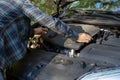 Man inspecting the car engine under the open hood while checking mechanical parts and trying to identify the cause of roadside Royalty Free Stock Photo