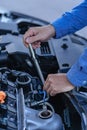 Man inspecting and fixing his car using wrench while working on broken engine on road Car Royalty Free Stock Photo