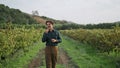 Man inspecting grape plantation walking road between grapevine rows. Vineyard