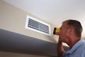 Man Inspecting a Home Rectangle Wall Air Vent with a Flashlight Royalty Free Stock Photo