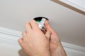 Man is installing electrical light bulb in the ceiling. Maintenance repair works in the flat. Restoration indoors Royalty Free Stock Photo