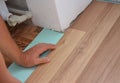 Man Installing Laminate Wood Flooring in Problem Area. Worker Installing wooden laminate flooring.