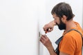 Man installing light switch after home renovation. Electrician mounting electric sockets on the white wall