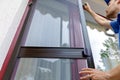 Man installing mosquito net wire mesh on house balcony door