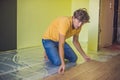 Man installing new wooden laminate flooring. infrared floor heat Royalty Free Stock Photo