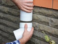 Man installing plastic rain gutter system pipeline. Guttering, Gutters, Plastic Guttering, Guttering & Drainage by Handyman hands. Royalty Free Stock Photo