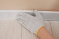 Man installing plinth on laminated floor in room, closeup Royalty Free Stock Photo