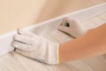 Man installing plinth on laminated floor in room, closeup Royalty Free Stock Photo