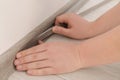 Man installing plinth on laminated floor in room, closeup Royalty Free Stock Photo