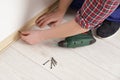 Man installing plinth on laminated floor in room, closeup Royalty Free Stock Photo