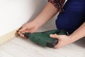 Man installing plinth on laminated floor with screwdriver in room, closeup Royalty Free Stock Photo