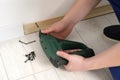 Man installing plinth on laminated floor with screwdriver in room Royalty Free Stock Photo