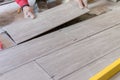 Man installing rectangular shaped floor tiles in kitchen. Applying adhesive before installation and verifying afterwards