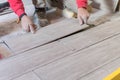 Man installing rectangular shaped floor tiles in kitchen. Applying adhesive before installation and verifying afterwards