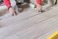 Man installing rectangular shaped floor tiles in kitchen. Applying adhesive before installation and verifying afterwards