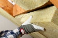 Man installing thermal roof insulation layer - using mineral woo