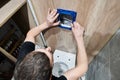 Man installing toilet flush system in bathroom.