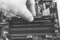 Man installs an DDR 4 DIMM 16 Gb Kingston HyperX Fury Memory RAM Module in the slot on the motherboard closeup, black and white ph Royalty Free Stock Photo