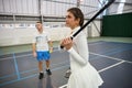 Man instructor helps woman learn tennis they practice hitting ball Royalty Free Stock Photo