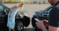 Man insurance agent inspects damage to a woman car and makes notes on a smartphone. Man inspecting broken car. Insurance Royalty Free Stock Photo